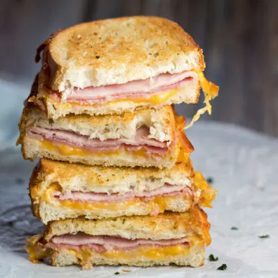 large square image of stacked halves of crispy, cheesy Air Fryer Grilled Ham and Cheese sandwiches.