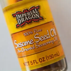 Large square closeup image of labeled sesame seed oil bottle.