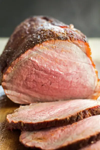 tall image of sliced smoked beef roast.