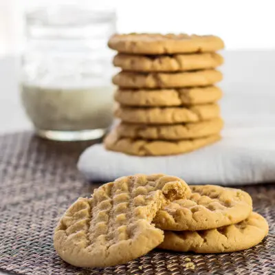 large square peanut butter cookies served with a glass of milk.