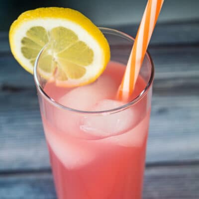 large square pink vodka lemonade served with a lemon slice.