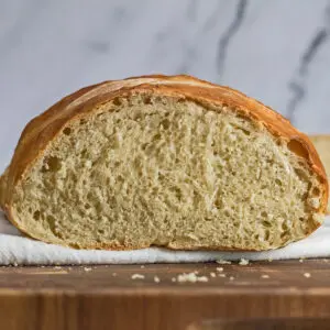 large rustic bread loaf sliced open on wooden cutting board.