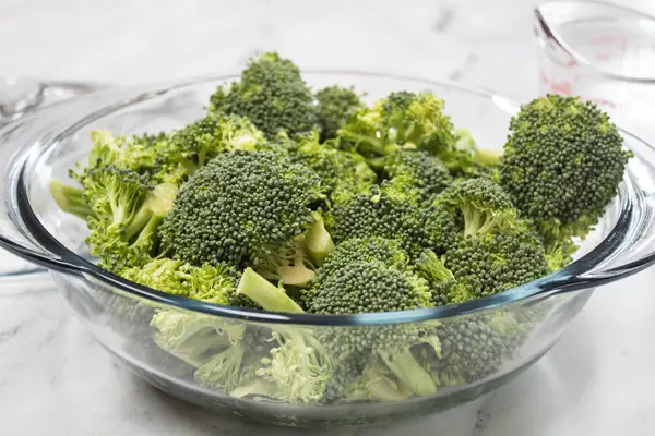 Broccoli florets in microwave safe bowl with water.