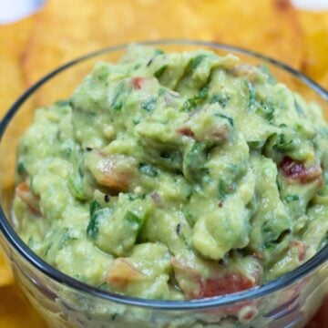 wide image with bowl of guacamole and tortilla chips.