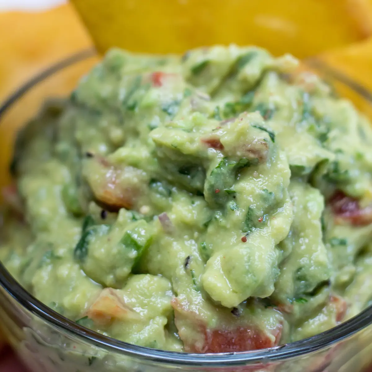 large square image with bowl of guacamole and tortilla chips.