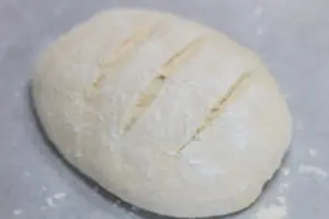 shaped rustic bread loaf with slits before baking.