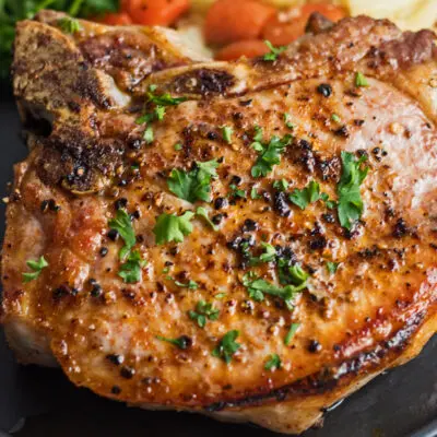 Wide image of cast iron pork chops served with vegetables.