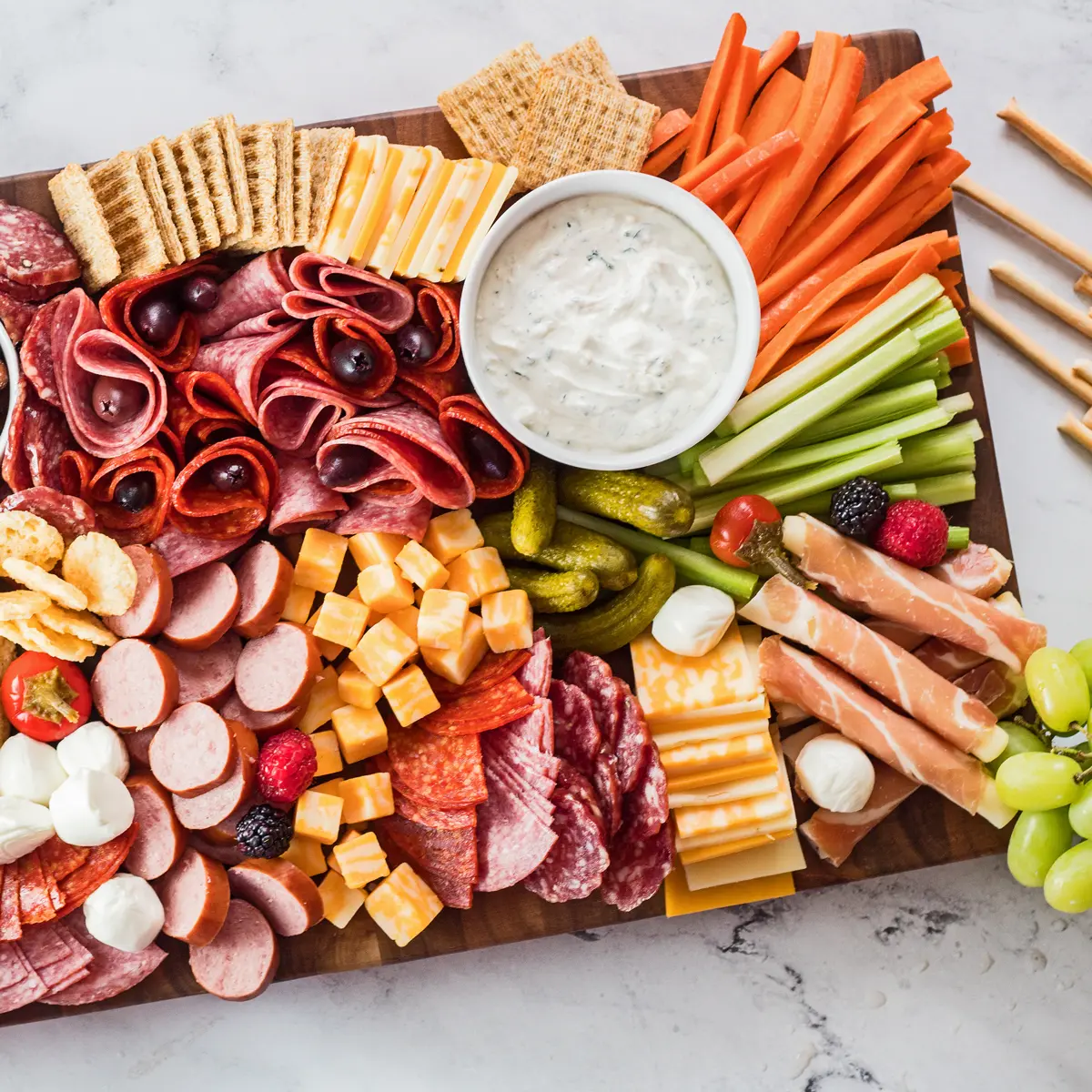 Planche apéro avec chiffre, garnie avec de la charcuterie, du fromage et  des crudités