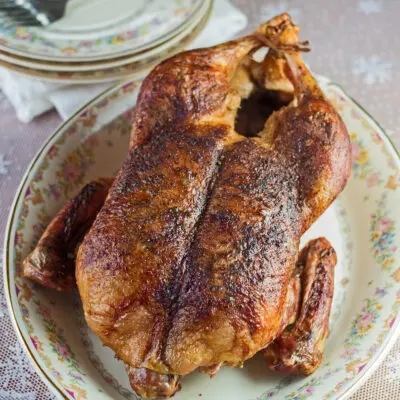 Large square image of whole roasted duck on serving platter.