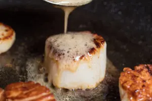 Baste the scallops with melted butter.
