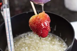 candy coating a large fresh strawberry.