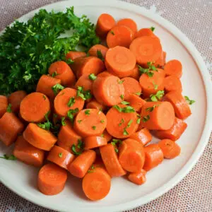 Large square overhead of microwave carrots with parsley garnish.