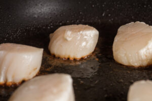 Sea scallops with the first side seared and ready to flip.