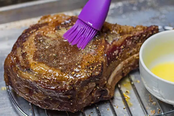 Basting the tomahawk steak with butter before searing.