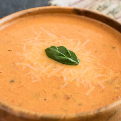 Image large de la soupe super crémeuse aux tomates rôties et au basilic.
