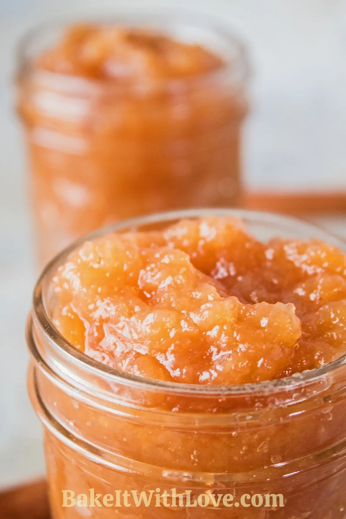 Homemade crock pot applesauce in jars with cinnamon sticks.