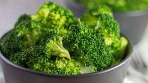 Närbild på mikrovågsugn ångad broccoli i svart skål.