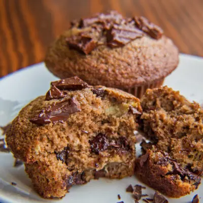 Protein powder chocolate banana muffins with one split open in front.