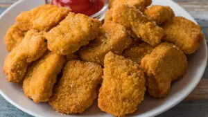 Wide image of the air fryer frozen chicken nuggets on white plate.