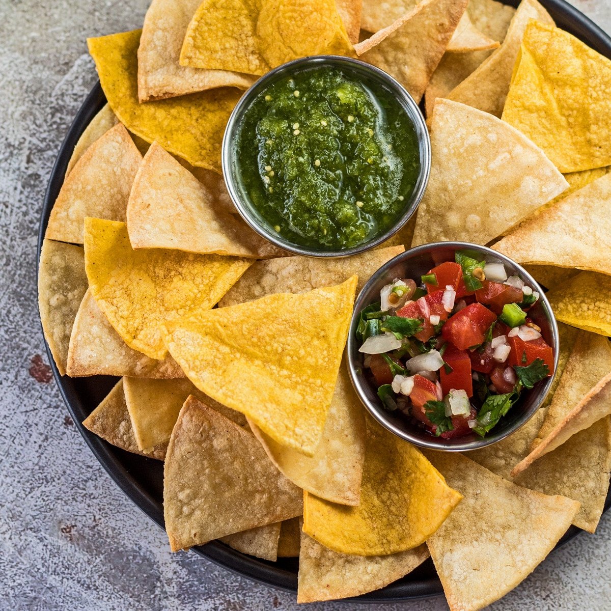 Tortilla chips de freidora servida con pico de gallo y salsa verde.