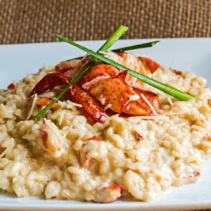 Creamy lobster risotto garnished with lobster claw and chives.