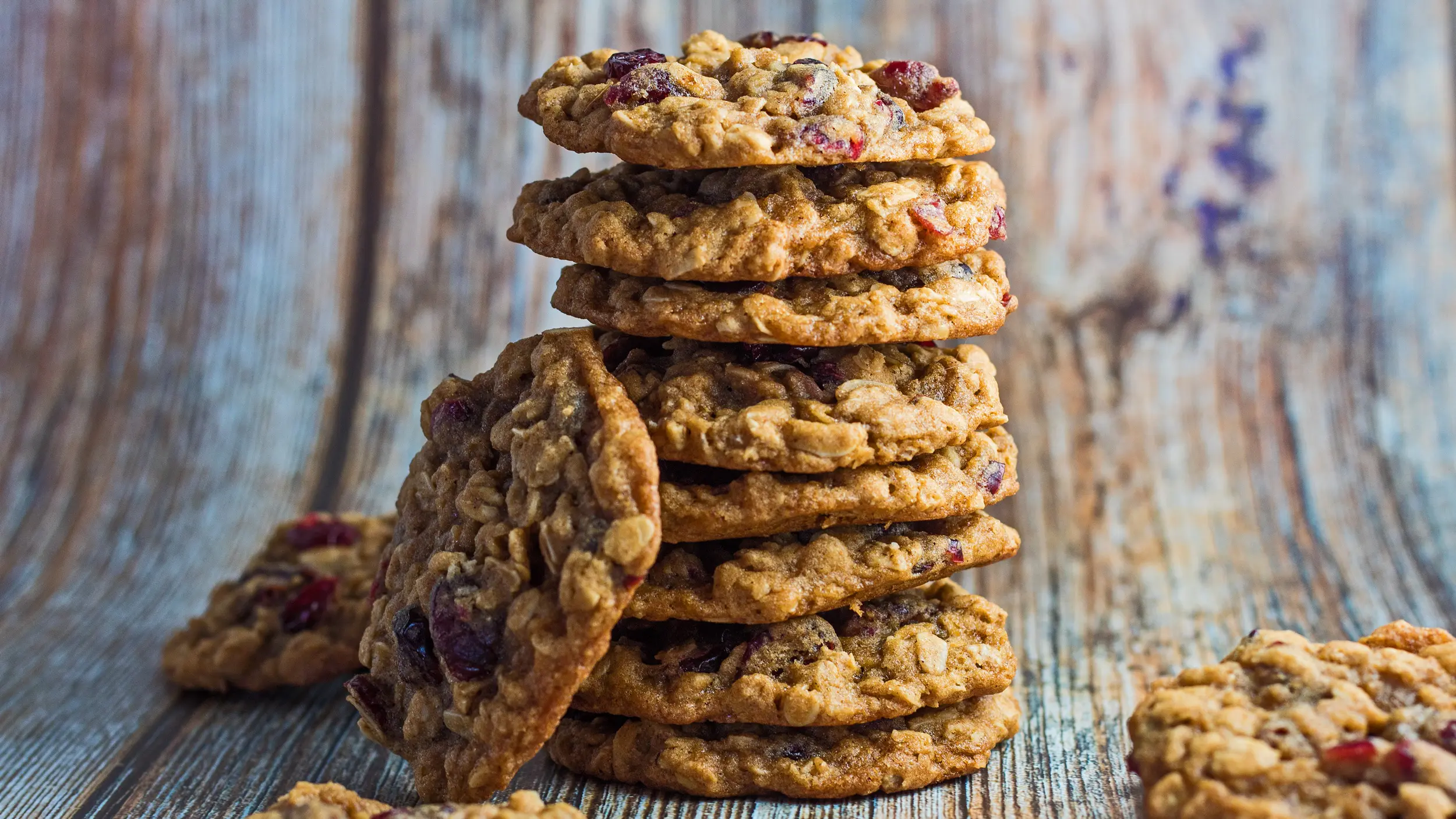 Oatmeal craisin cookies stacked with wooden grain background.
