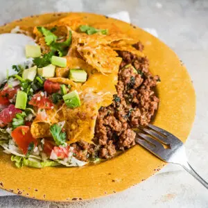 Walking taco casserole served with lettuce, sour cream, pico de gallo, and avocado.