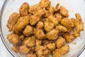 Orange chicken tossed and coating the chicken pieces.