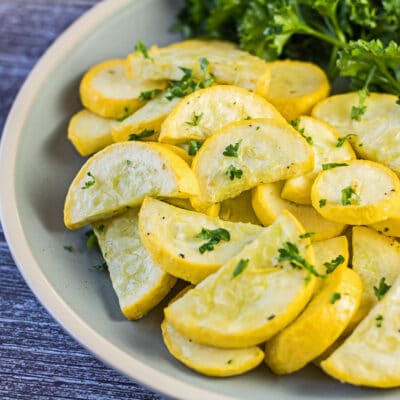 Air fryer yellow squash served on light green plate and garnished with parsley.