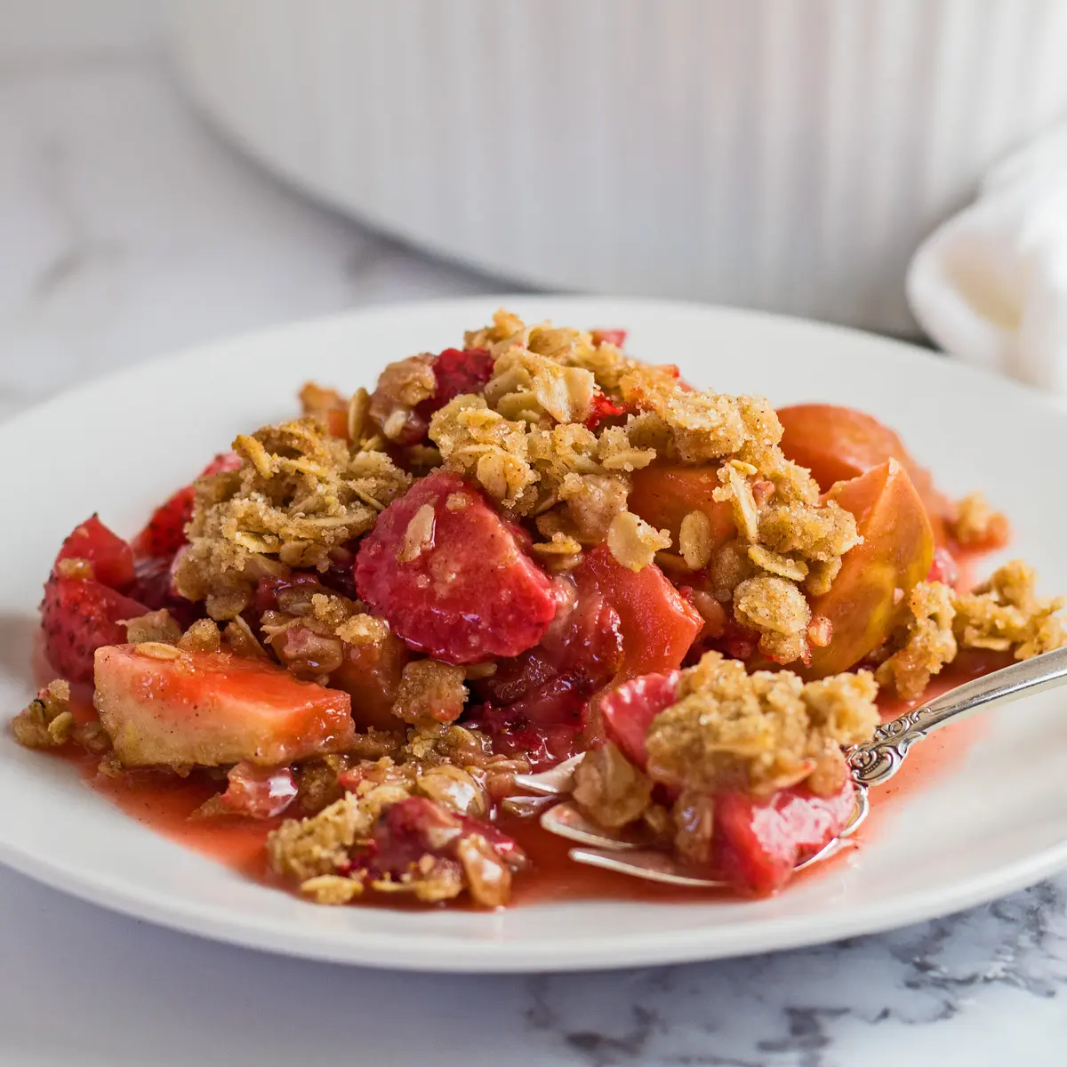 Apple strawberry crisp on a white plate.