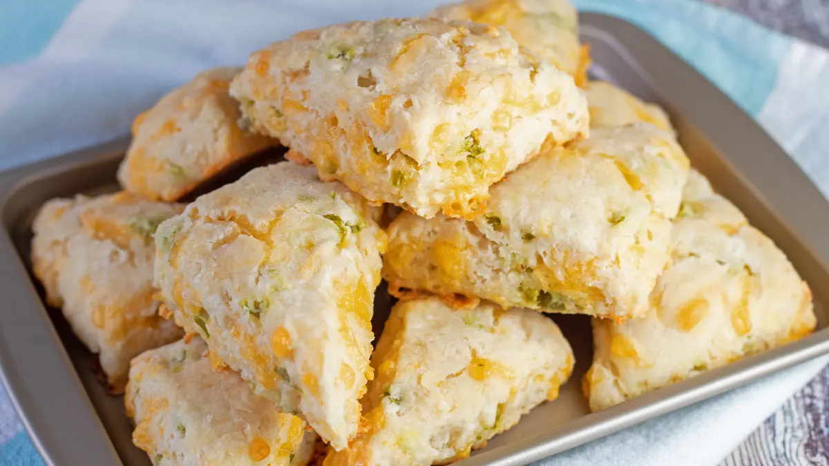 Jalapeno Cheddar Scones piled up on a baking tray with a blue and white background.