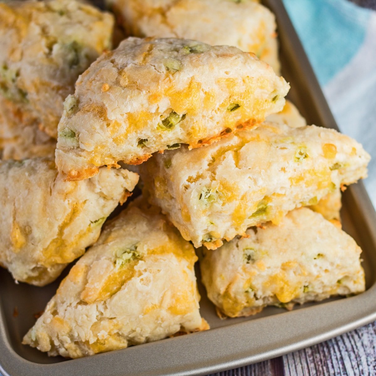Jalapeno Cheddar Scones piled up on a baking tray with a blue and white background.