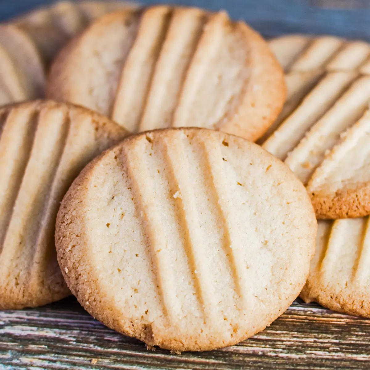 Вилични бисквити, изпечени до златисто и произволно натрупани върху дървения зърнен фон.