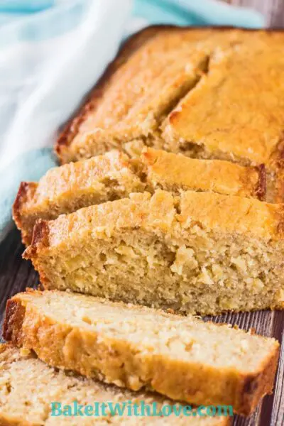 Sliced pineapple banana bread on wooden grain background.