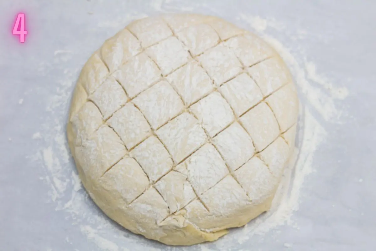 Process photo of shaped loaf coated with flour and scored.