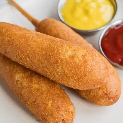 Air fryer corn dogs after cooking to crispy perfection and served with ketchup and mustard.