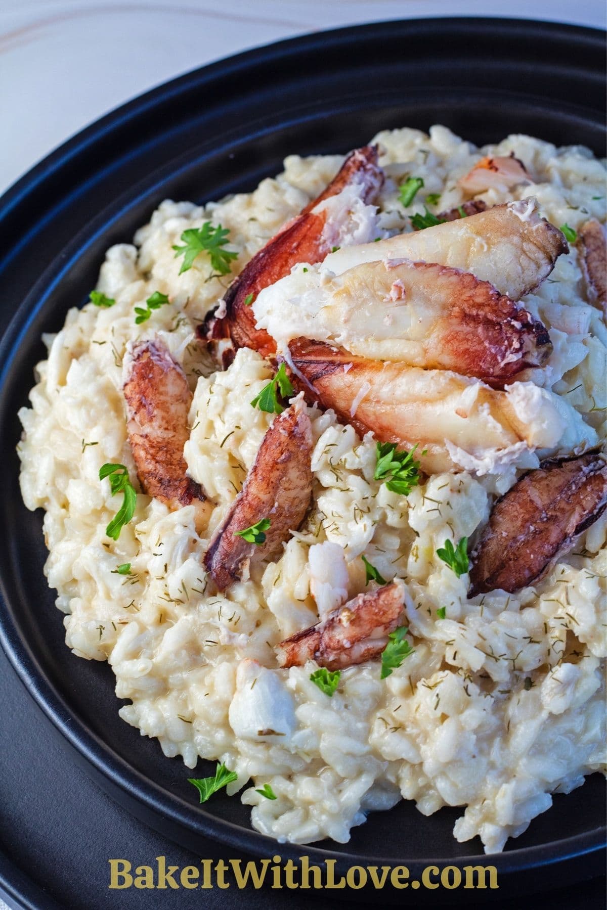 Crab risotto served on blackplate with crab meat and parsley garnish.