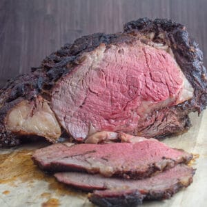 Smoked prime rib shown sliced open on wooden cutting board.