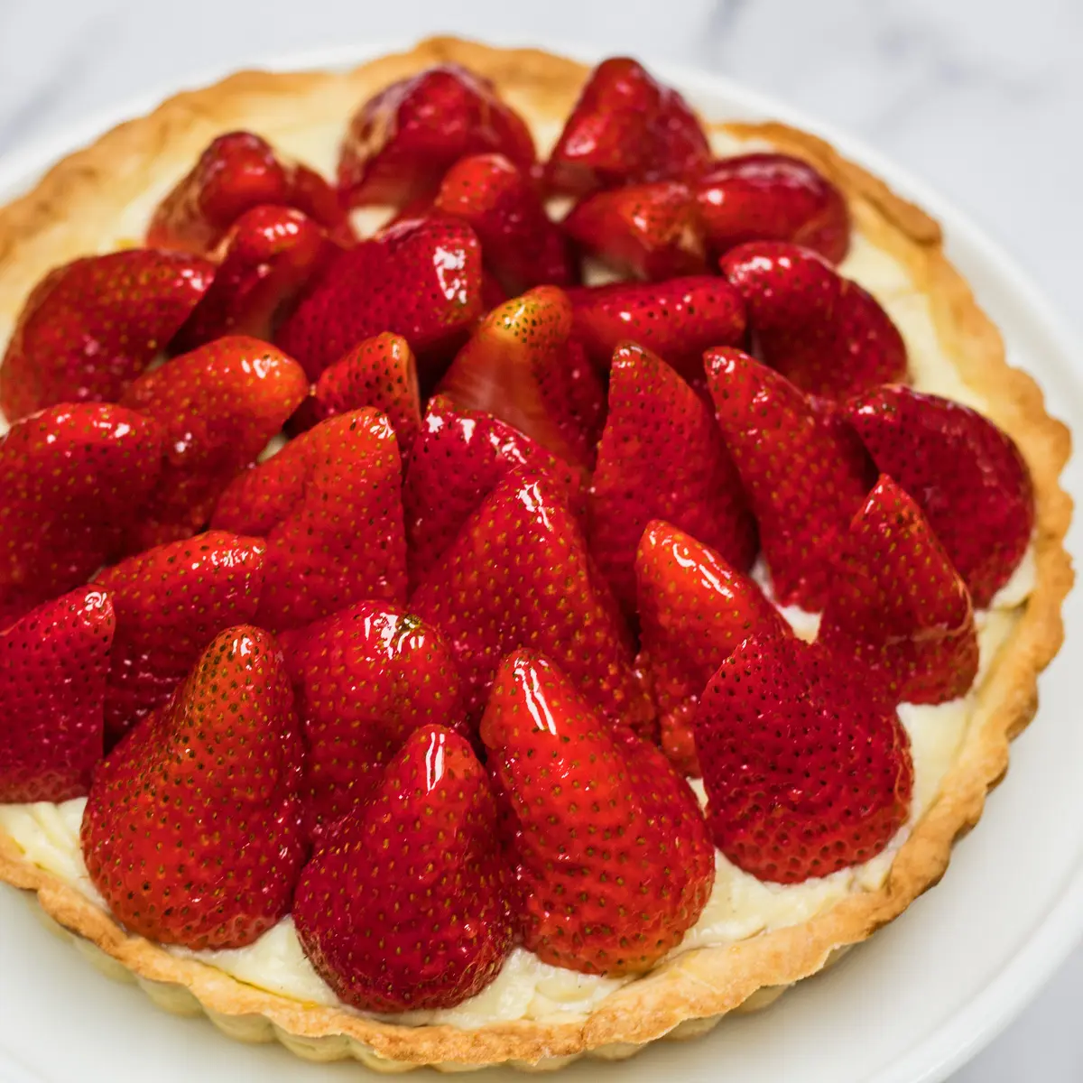Tarte aux Fraises the classic French strawberry tart shown on white cake stand.