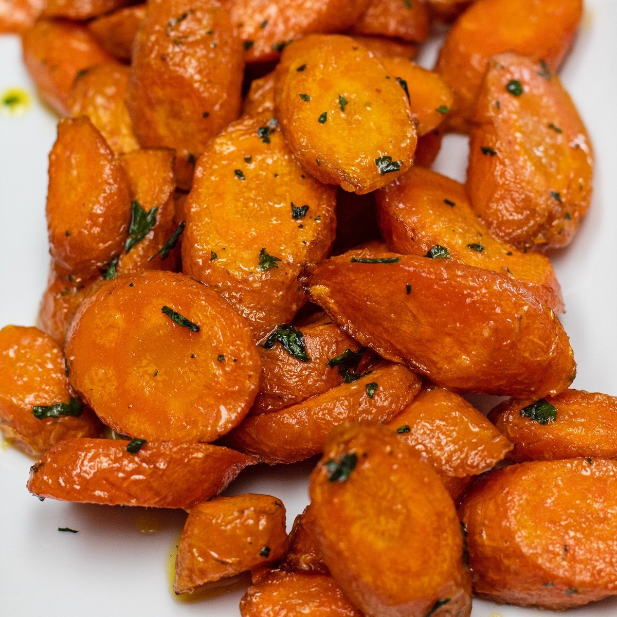 Gemakkelijke worteltjes uit de airfryer gekookt tot in de perfectie en geserveerd op een wit bord.