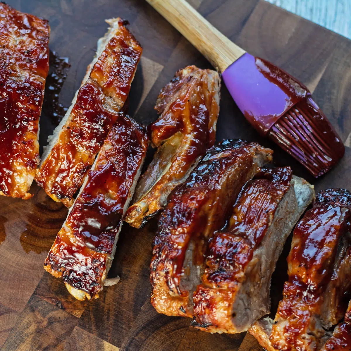 Côtes de porc frites en tranches sur une planche à découper en bois foncé.