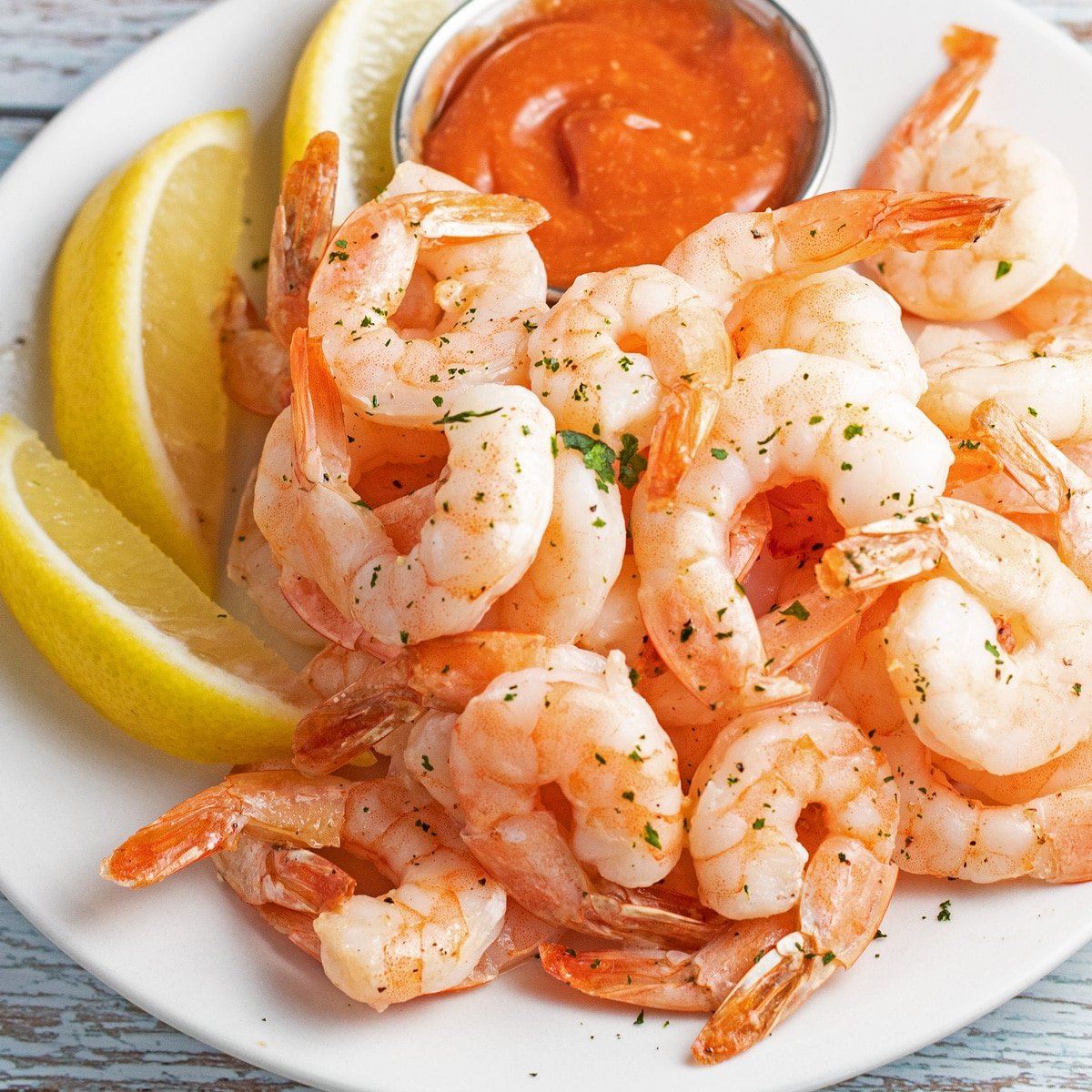 Air fryer shrimp served with lemon wedges and cocktail sauce.