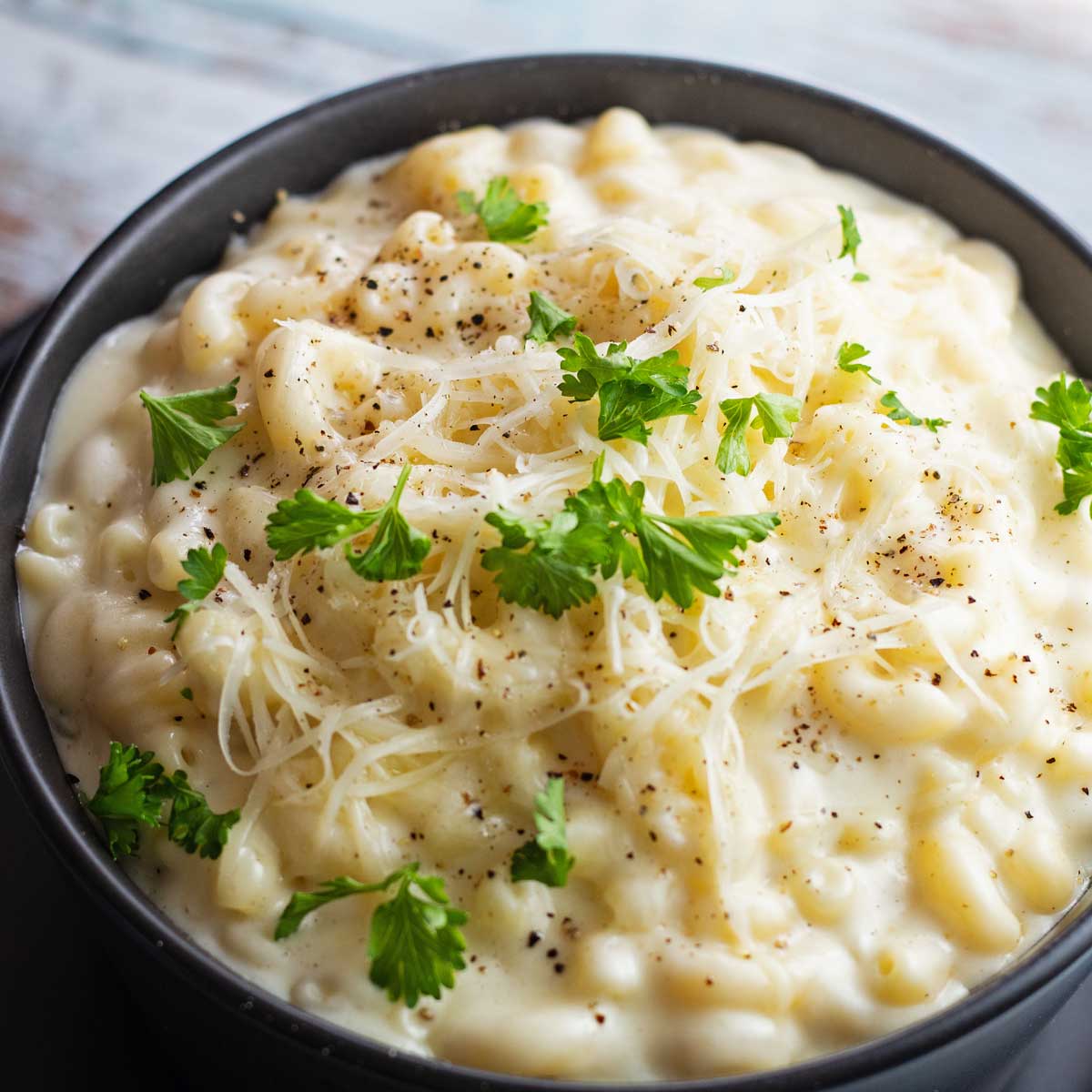 Creamy stovetop white cheddar mac and cheese served in black bowl.