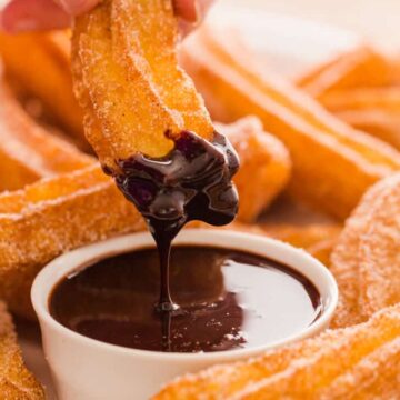 Churros dipping in chocolate sauce.