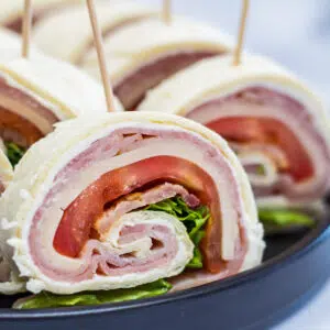 Club pinwheel sandwiches sliced and served on black plate.