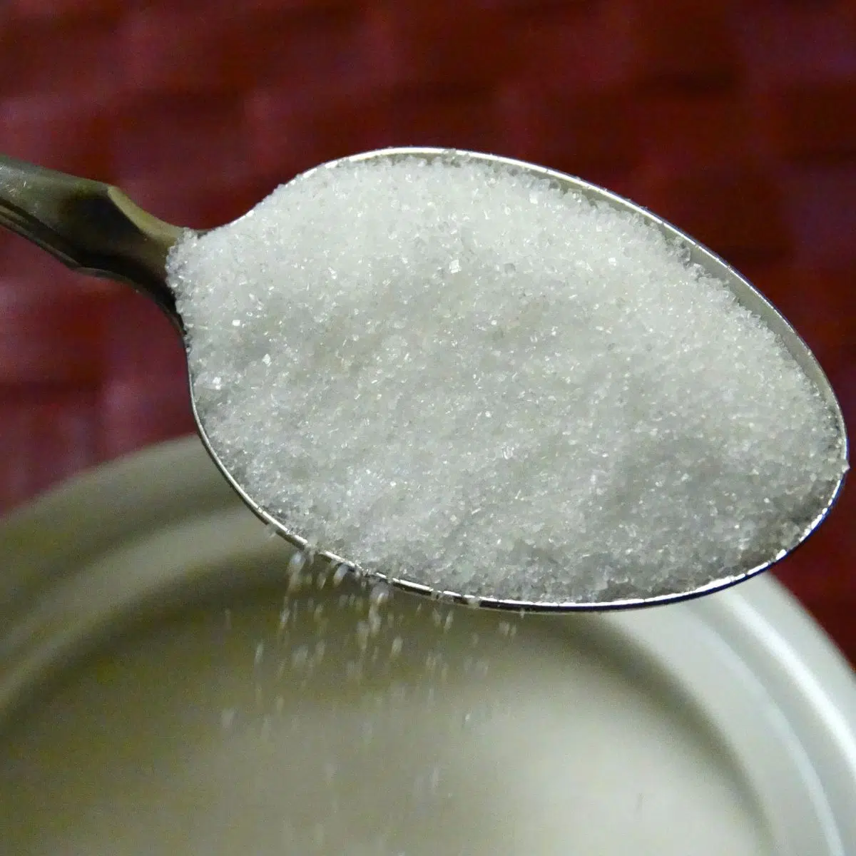 Zucker wird aus dem Behälter gelöffelt.