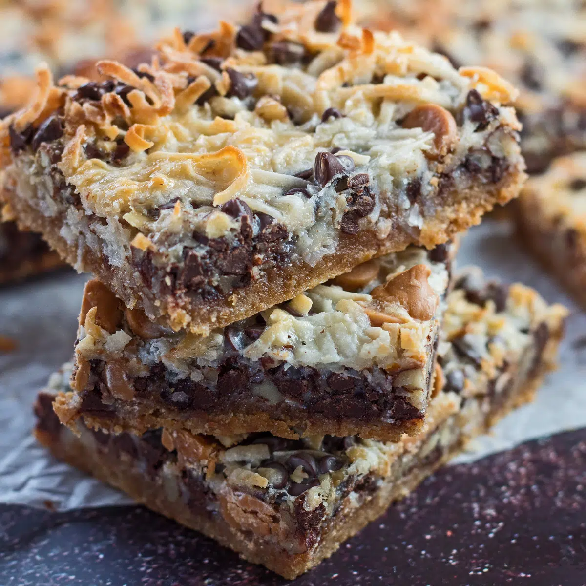 Stacked Hello Dolly Bars on parchment paper.