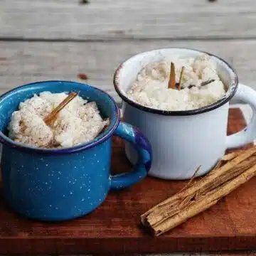 Arroz con Leche served in mugs on wooden cutting board.