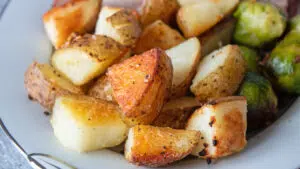 Crispy oven roasted potatoes served on platter with roast and vegetables.