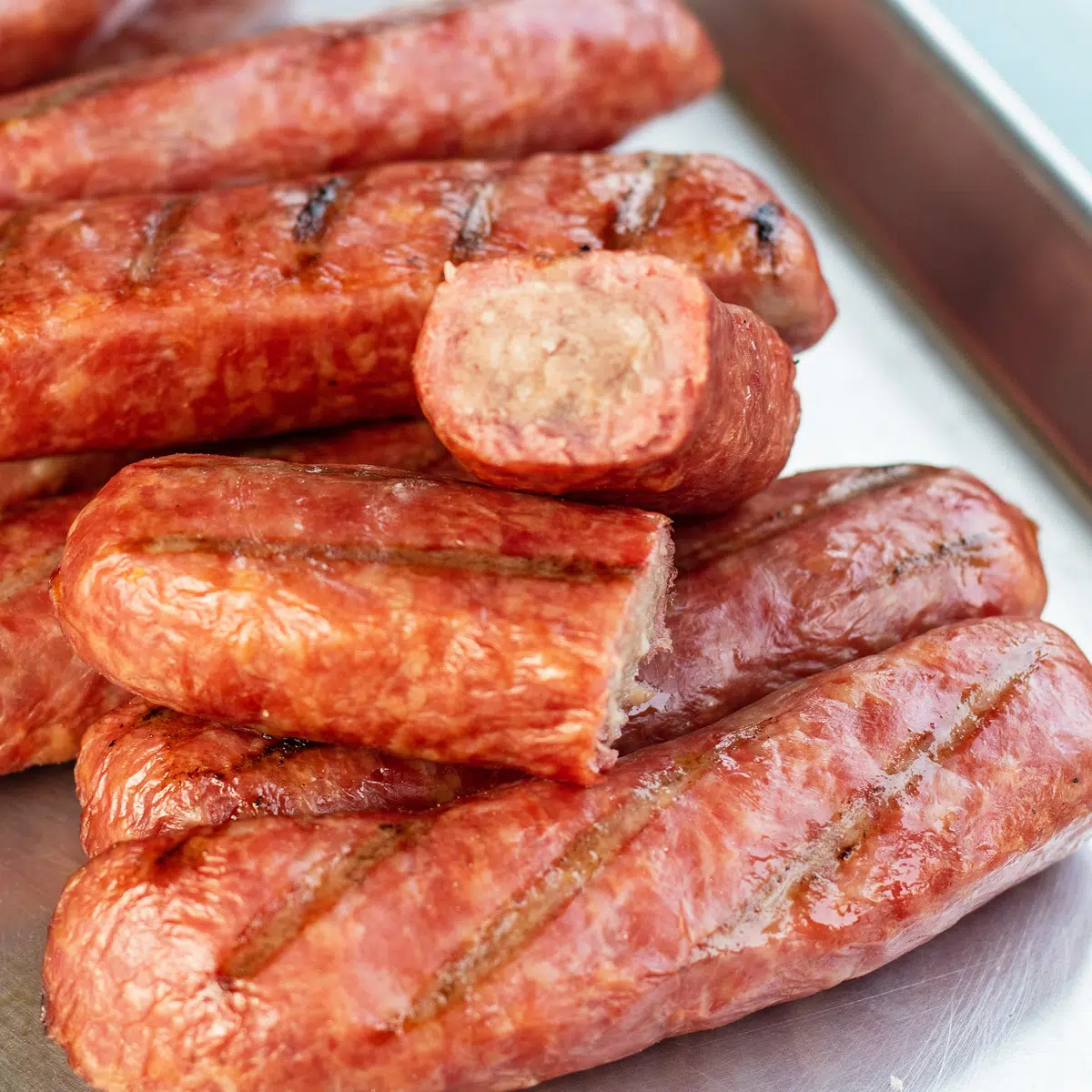 Smoked brats served on metal tray.